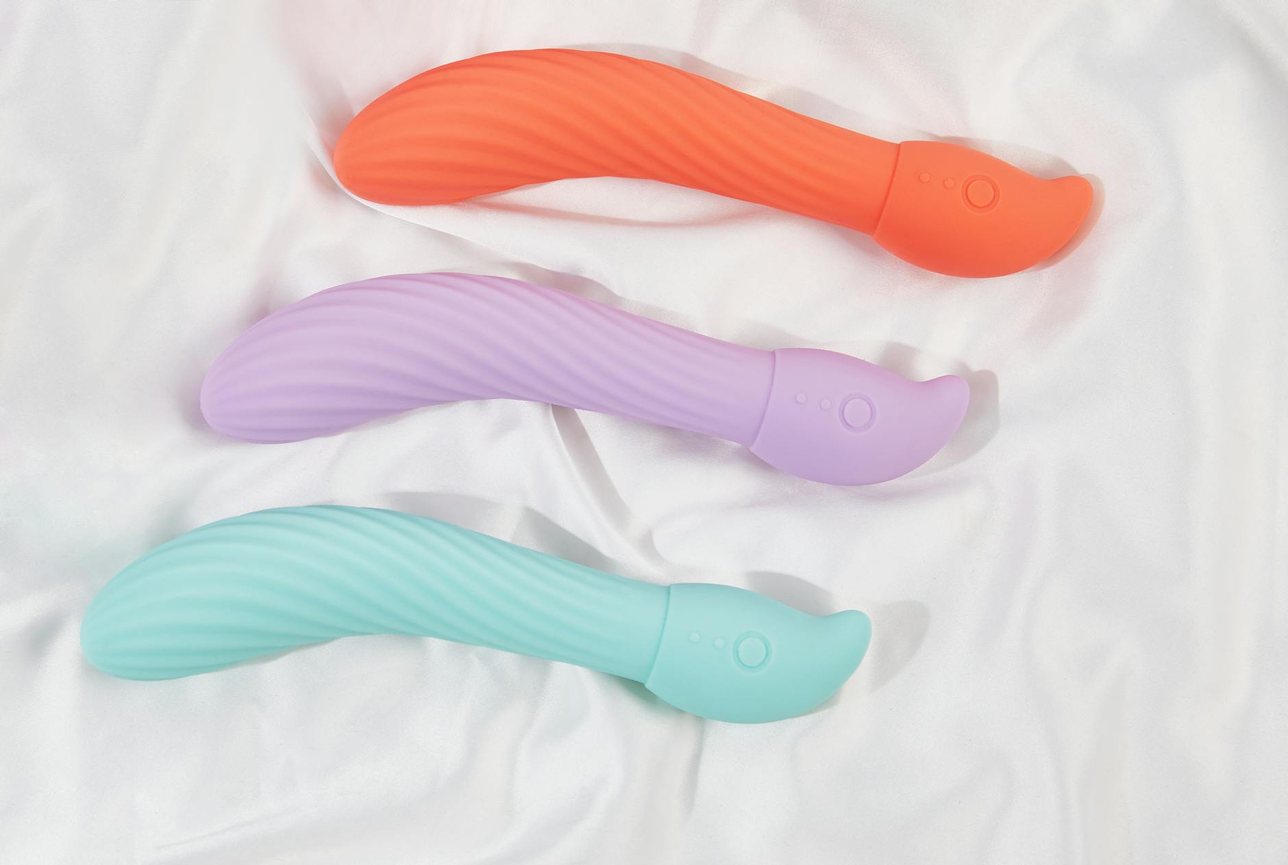A stylish teal vibrator on smooth white silk fabric