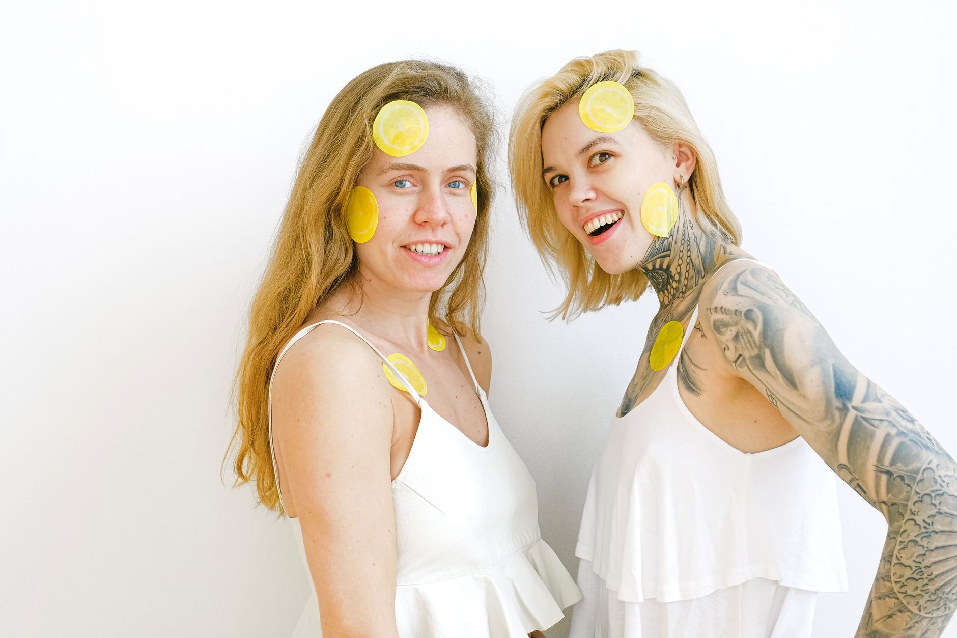 A blue vibrator surrounded by fresh citrus and flowers on a bright yellow background