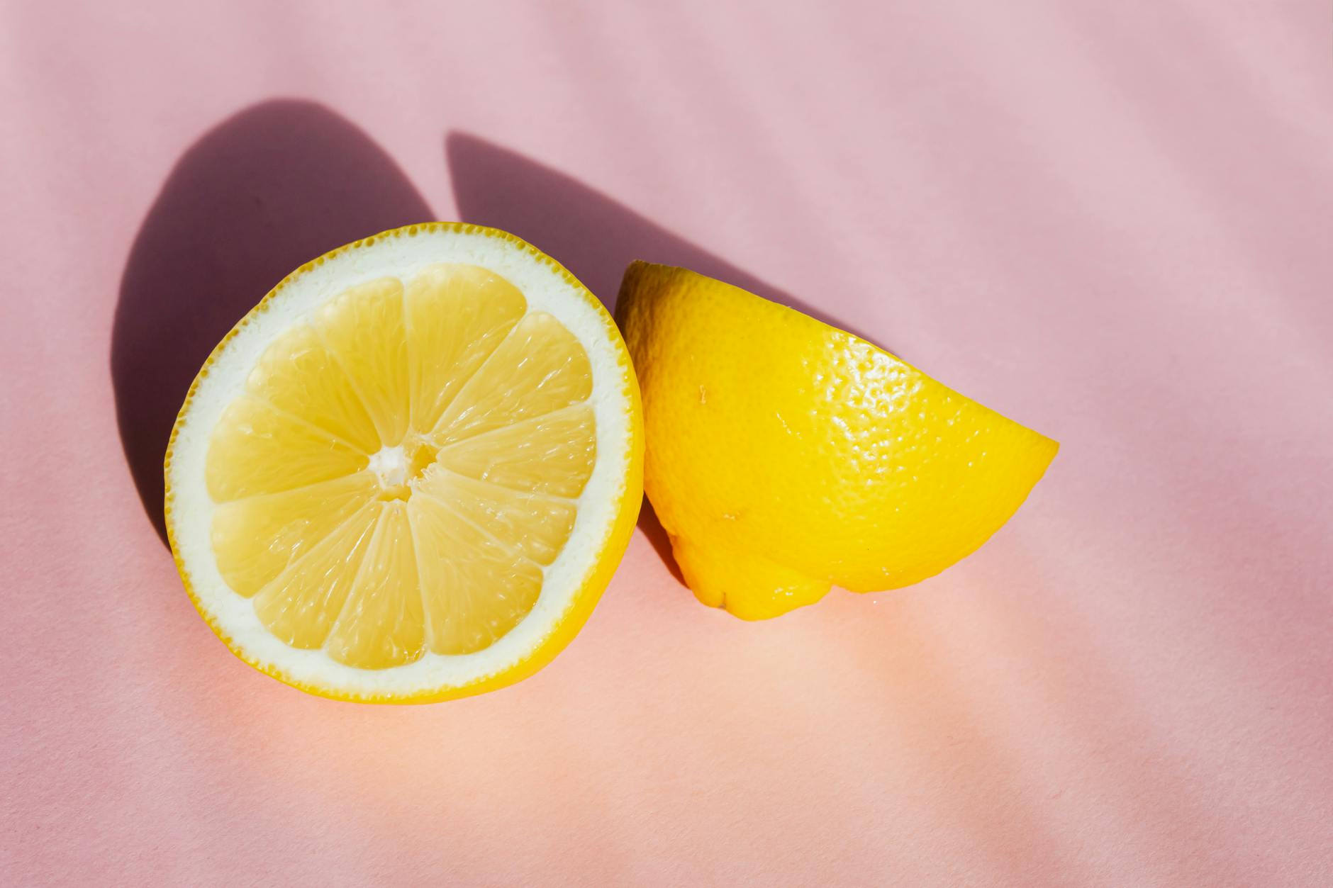 Fresh lemon halves on a pink background, symbolizing renewal and vitality