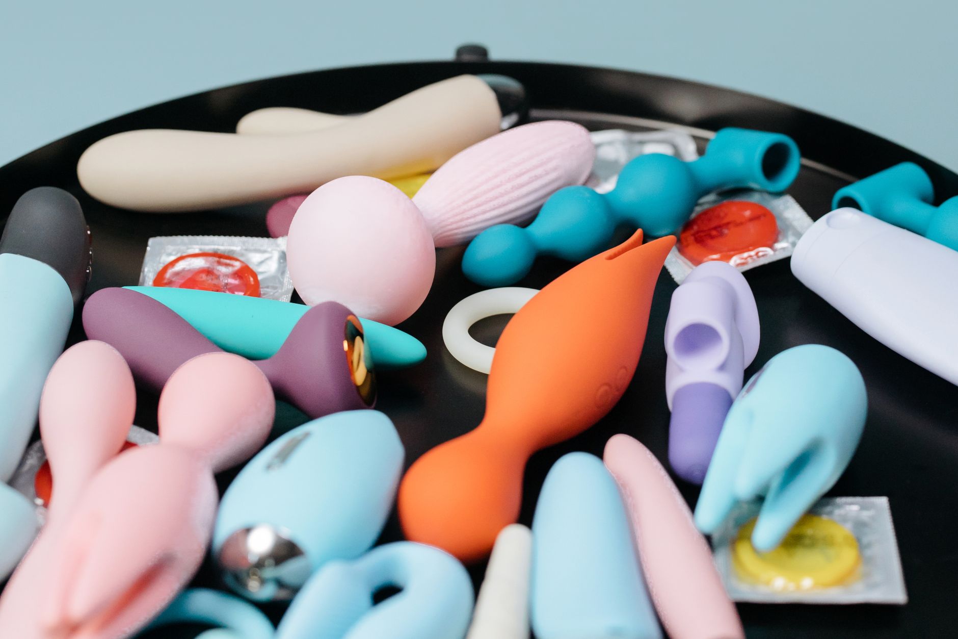 Two hands holding pastel-colored silicone vibrators, representing intimate exploration between partners