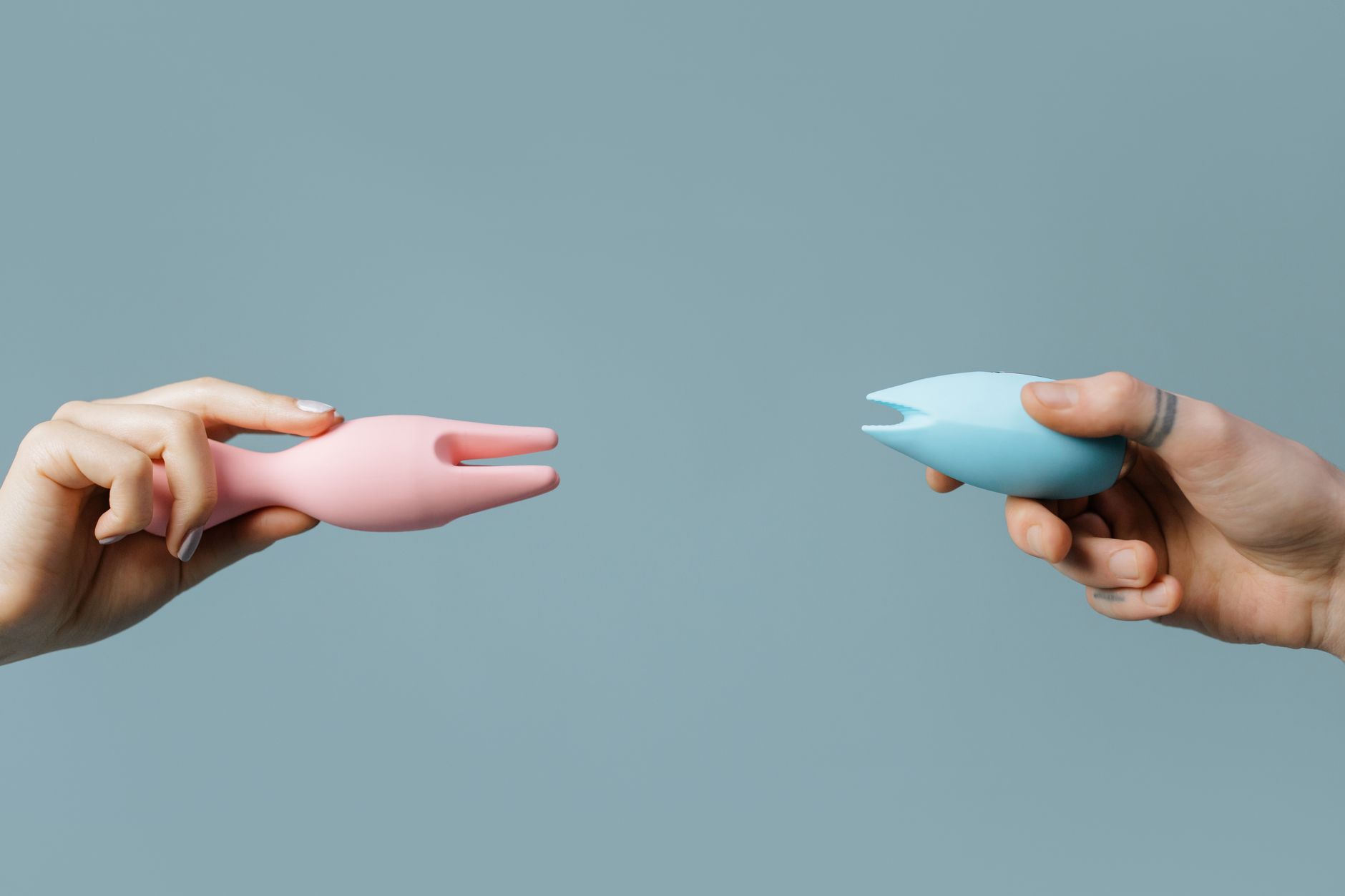 Hands holding pastel-colored clitoral vibrators, perfect for postpartum pleasure exploration