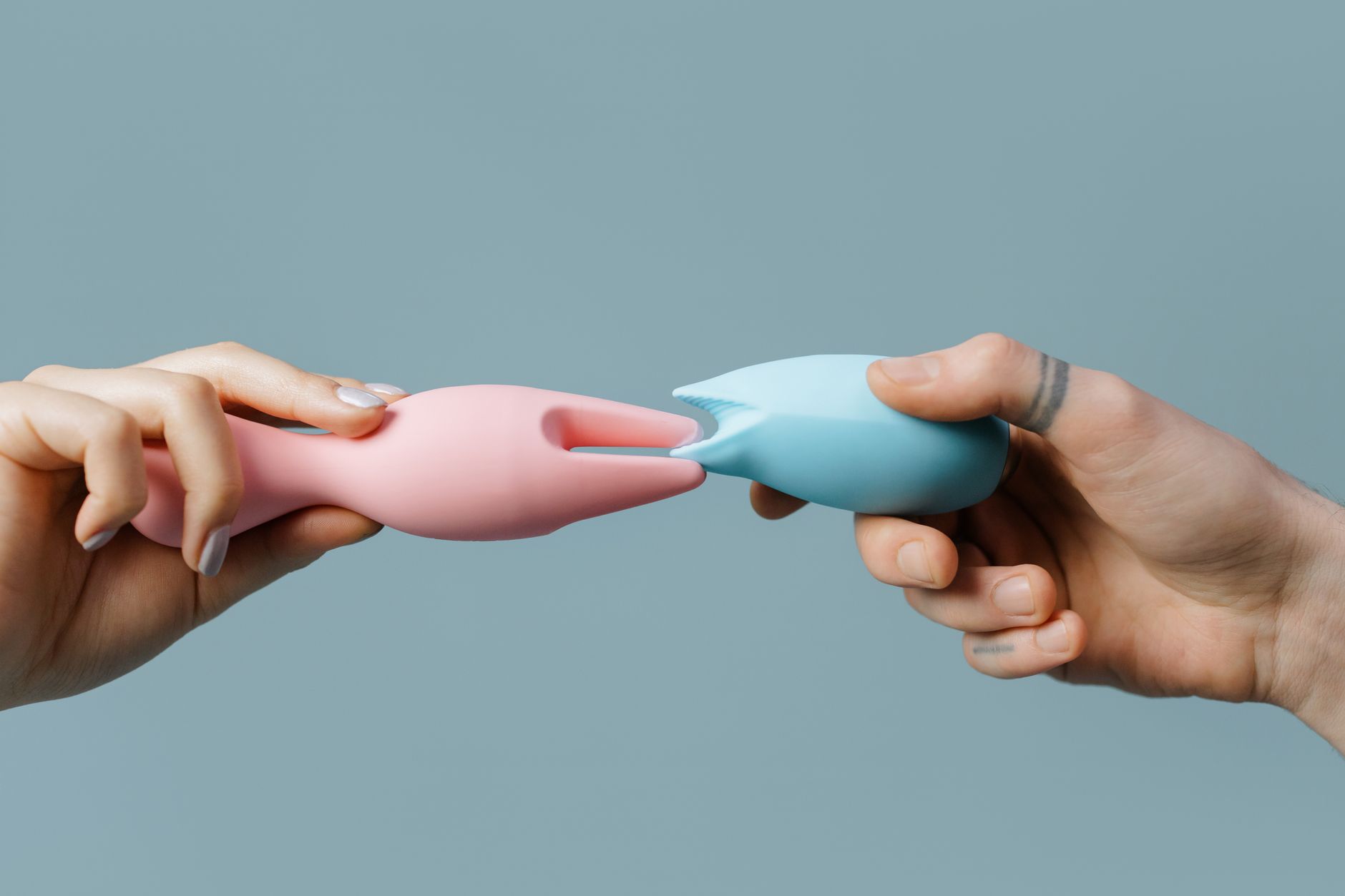 Woman holding blue and pink clitoral vibrators, representing couples choosing toys together for reconnection