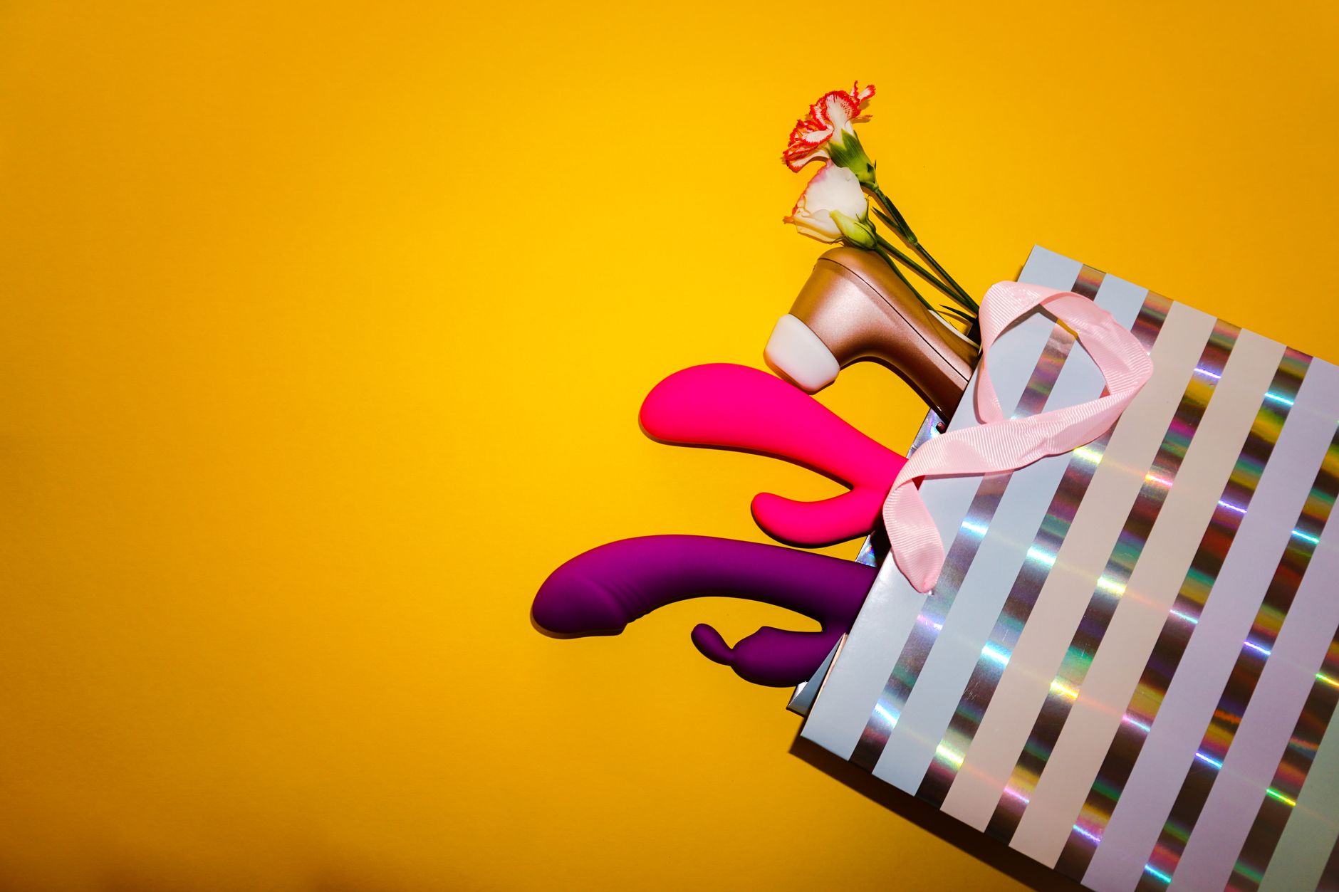 A hand holding a fresh lemon against a bright yellow background, symbolizing the citrus-inspired lemon vibrator design.