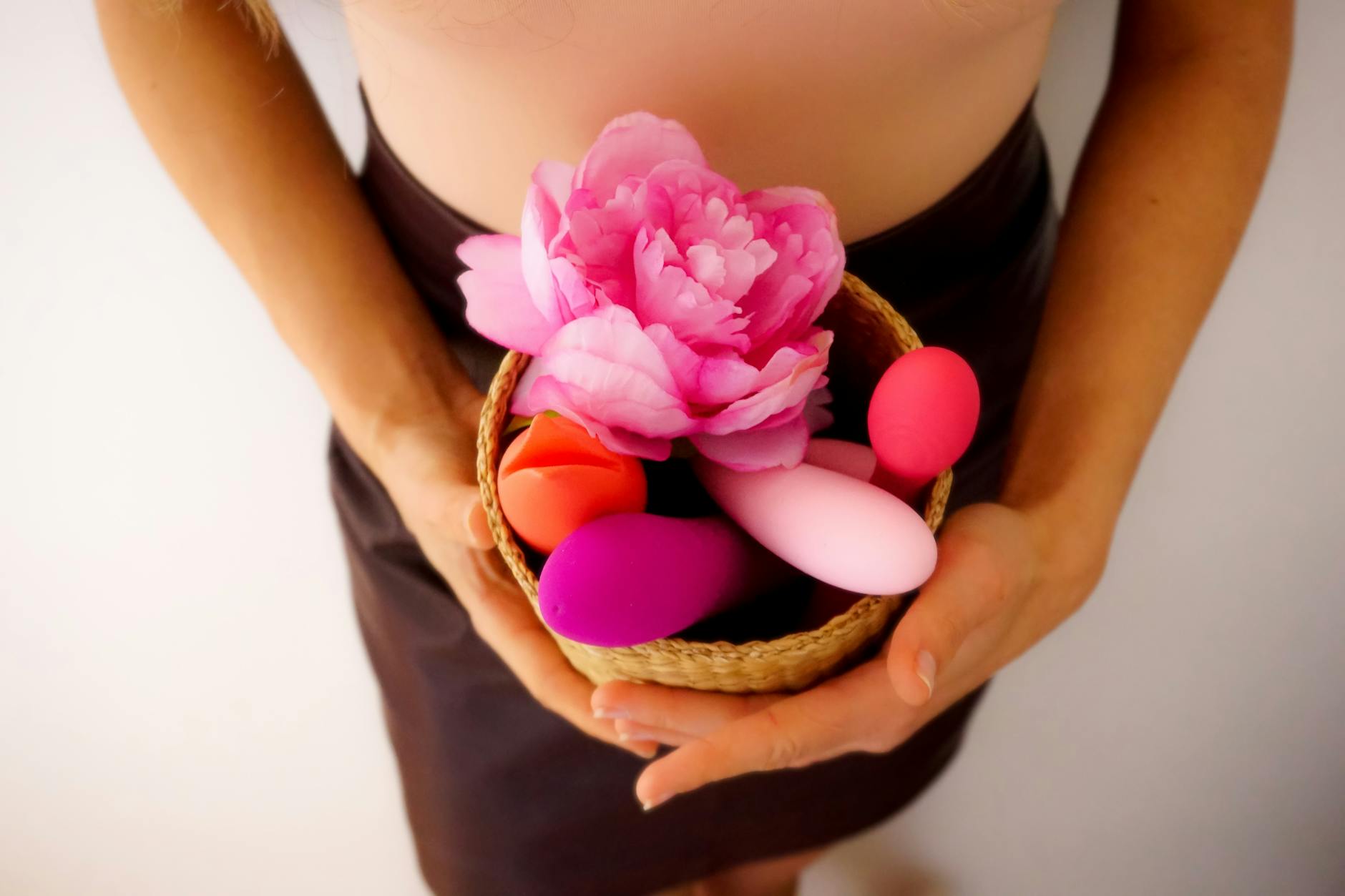 A hand holding colorful vibrators including lemon clitoral toys, representing accessible pleasure tools for burnout recovery.