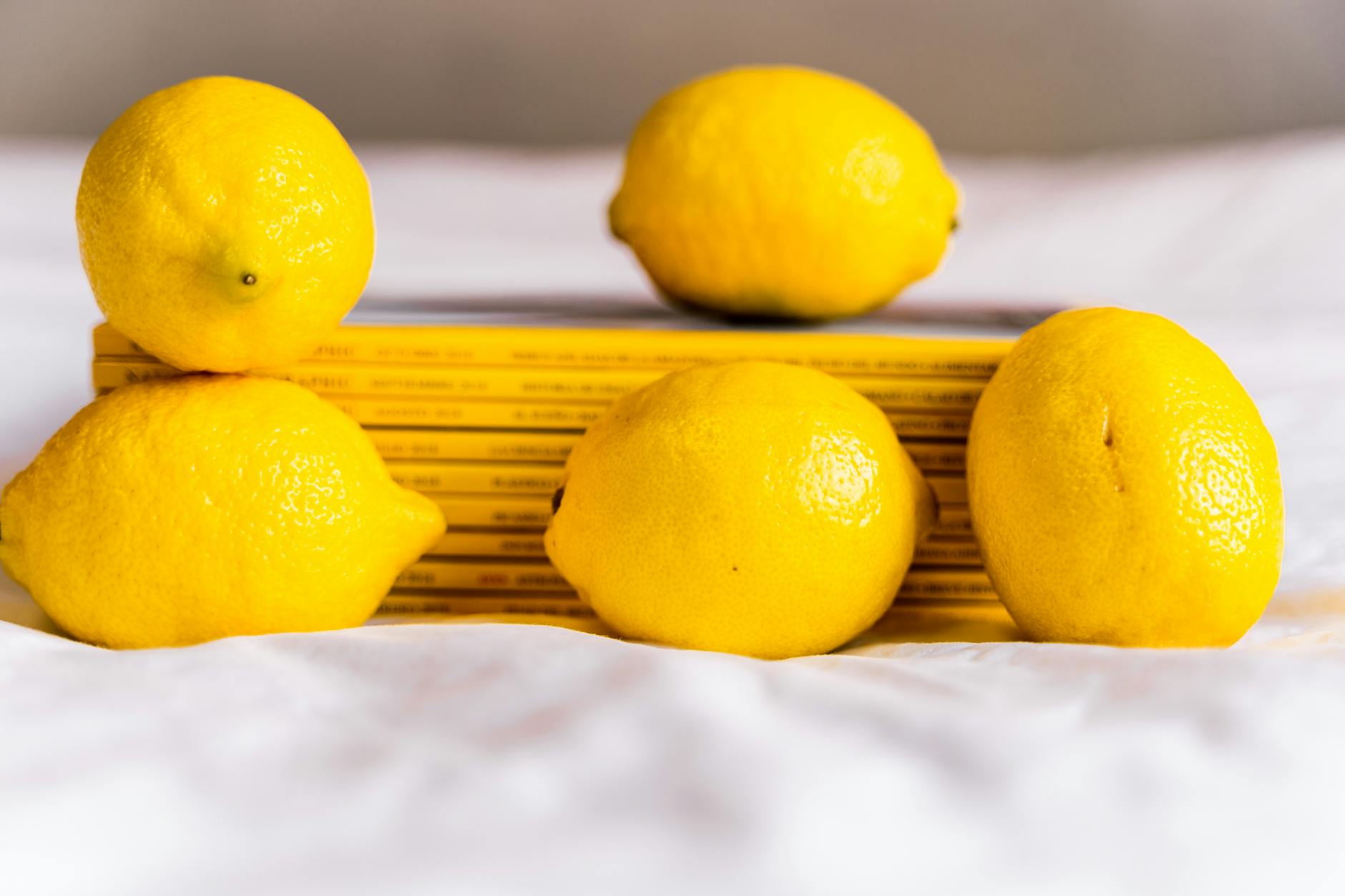 Hand holding a fresh lemon on soft pink background, symbolizing renewal and sensation